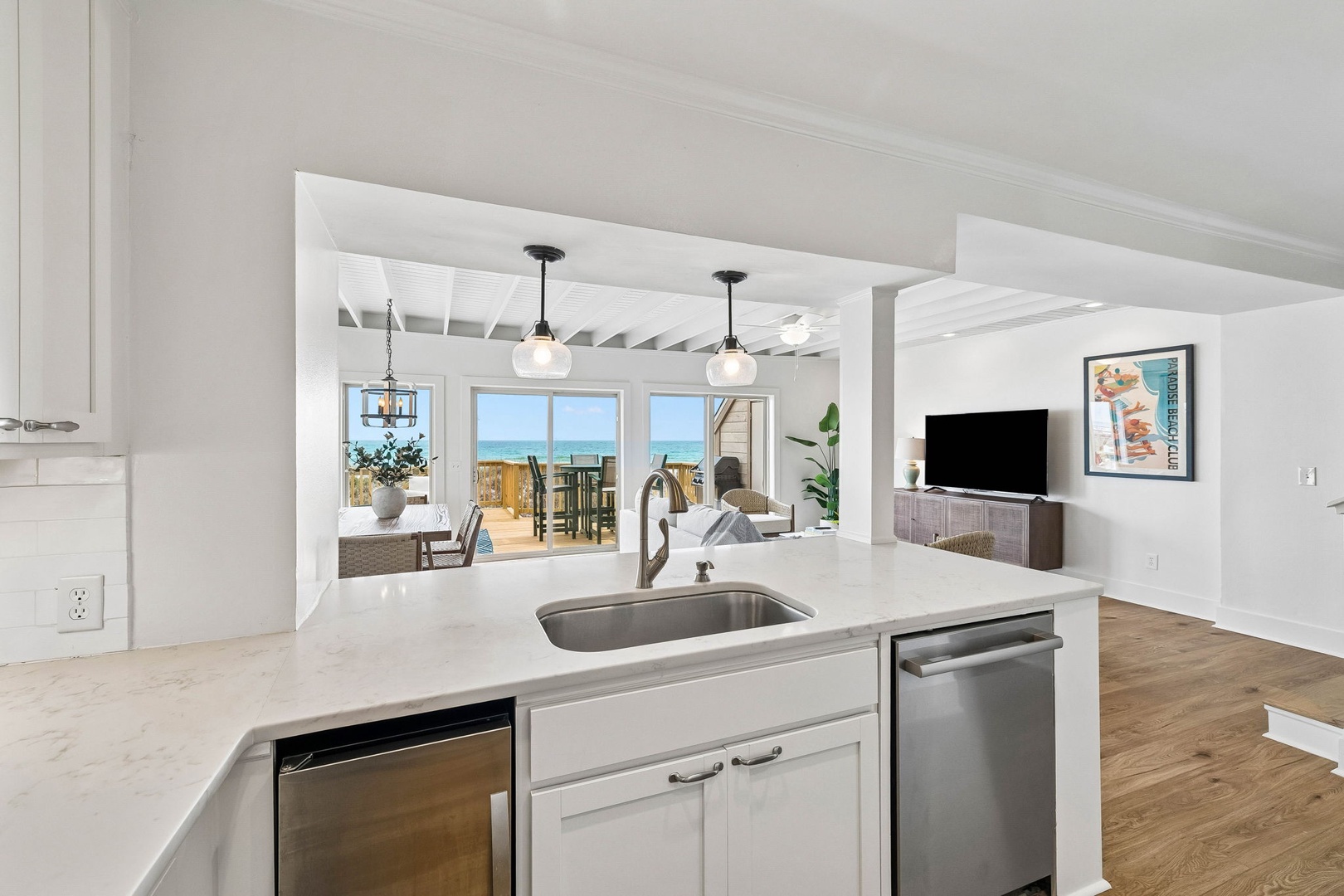 Picture yourself preparing meals on gleaming counters while glimpsing the sparkling ocean through wide windows. The open layout invites conversation as you cook, with the living area just steps away.