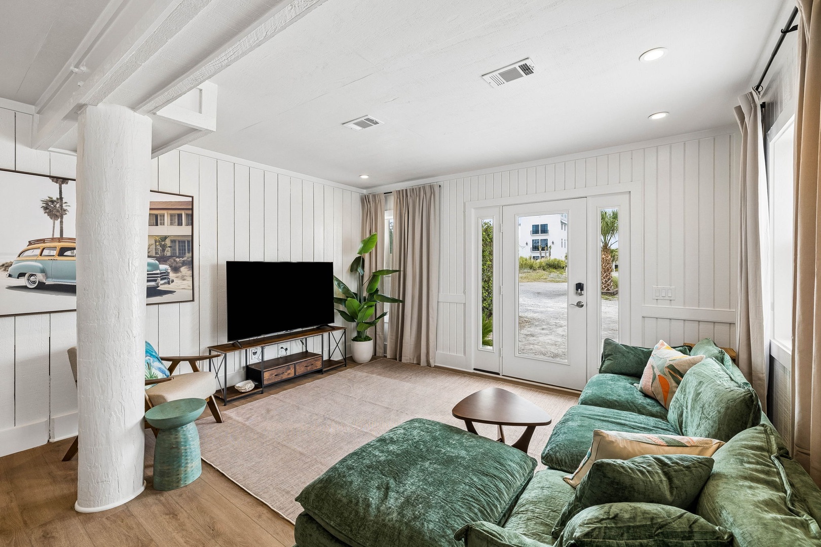 Sink into plush emerald sofas in your bright, beachy living room. Natural light floods through French doors, coastal vibes surround you, and entertainment awaits with your flat-screen TV.