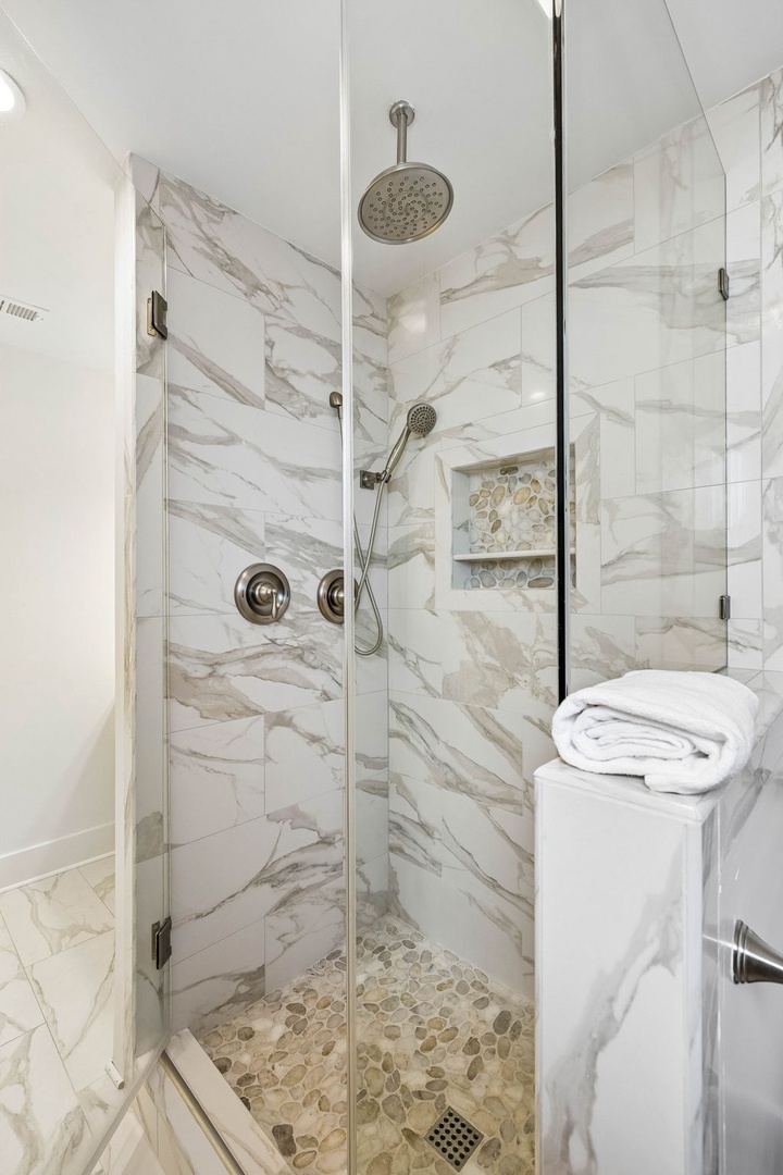 Step into your private spa with stunning marble-inspired tiles, dual showerheads, and luxurious river-stone flooring. Fresh towels await your arrival.
