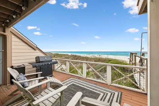 Beachfront deck overlooks pristine sands and turquoise waters, with a grill, lounge chairs, and sweeping coastal vistas perfect for sun-soaked mornings and evening gatherings.