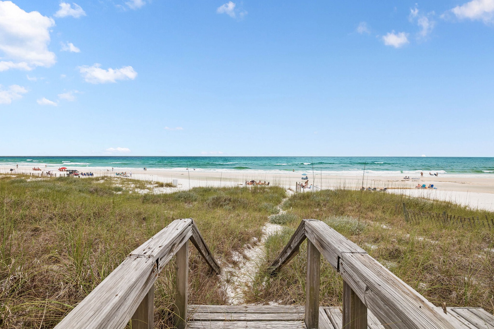 Direct beach access leads to pristine white sand and turquoise waters, perfect for sunbathing, swimming, and relaxation under clear skies.