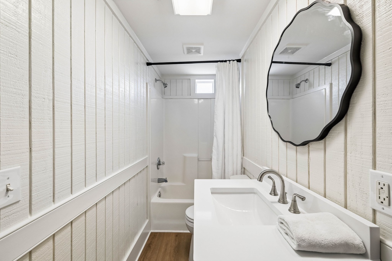 Bright, clean bathroom with coastal charm—fresh white shiplap, sleek fixtures, and your own bathtub to unwind in after a day of adventure.