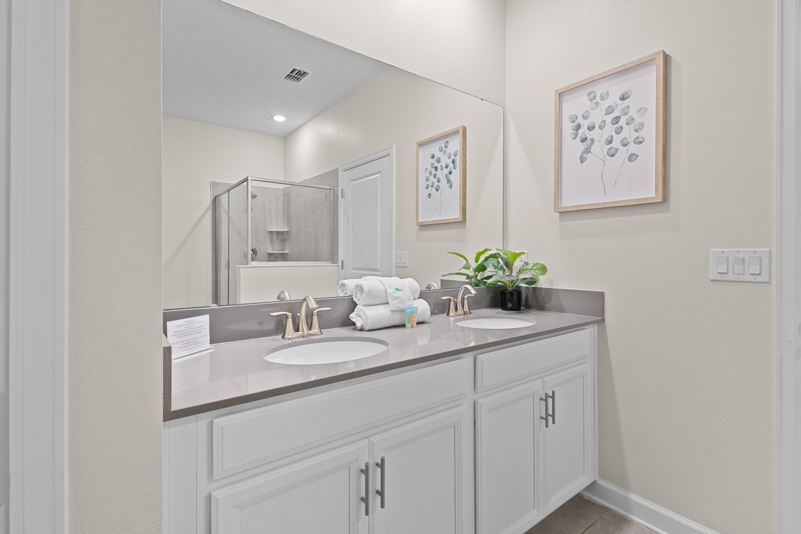 Step into your pristine bathroom with dual vanities, elegant countertops, and a spacious glass shower—perfect for your morning routine.