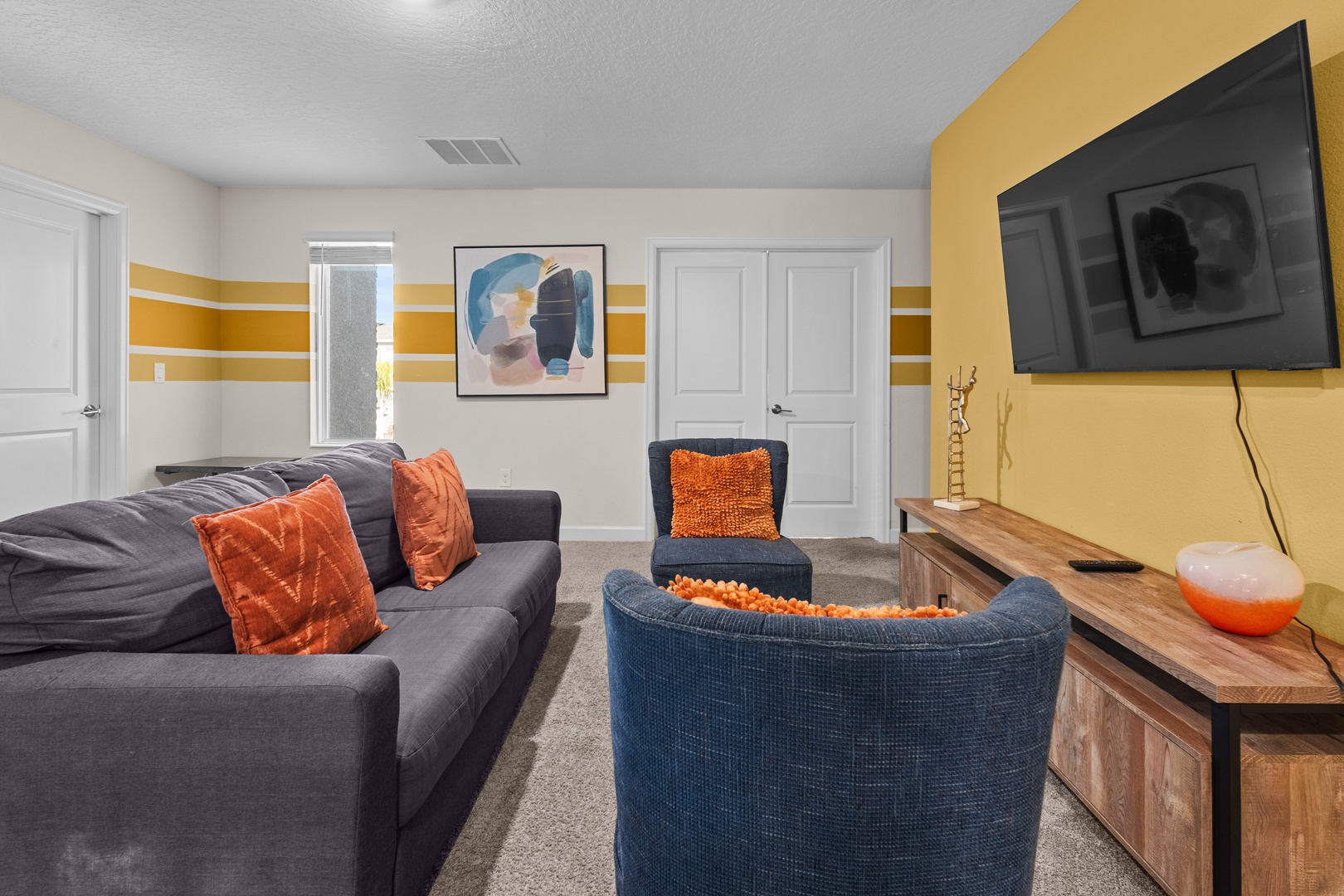 Settle into your stylish lounge with vibrant orange accents, plush seating, and entertainment center for perfect movie nights.