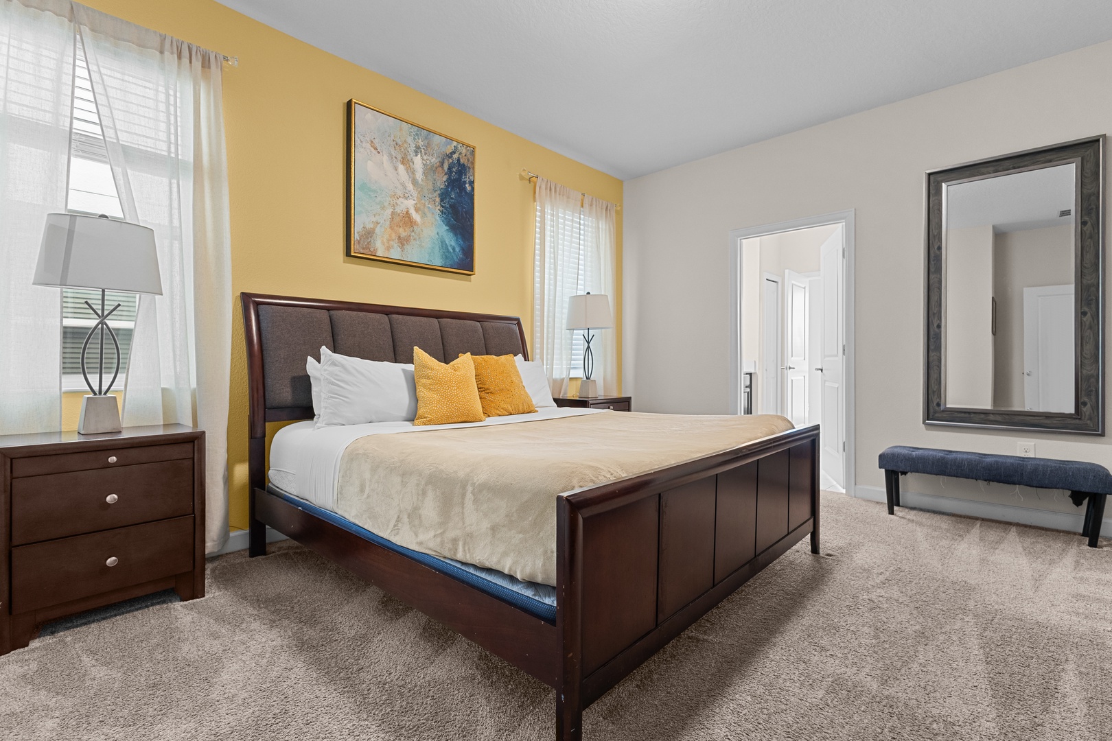 Rest peacefully in your elegant master bedroom featuring a plush king bed, warm lighting, and cheerful golden accent wall.