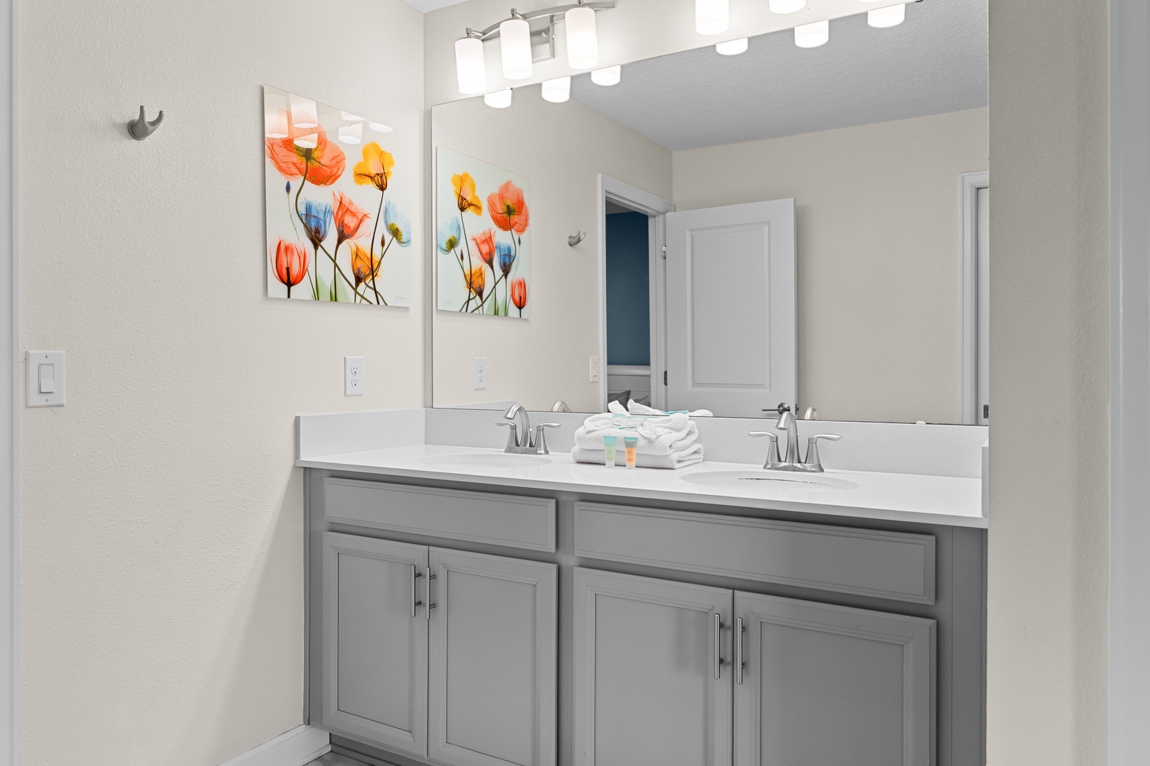 Freshen up in your bright, modern bathroom featuring dual sinks, ample counter space, and cheerful floral artwork to brighten your morning routine.