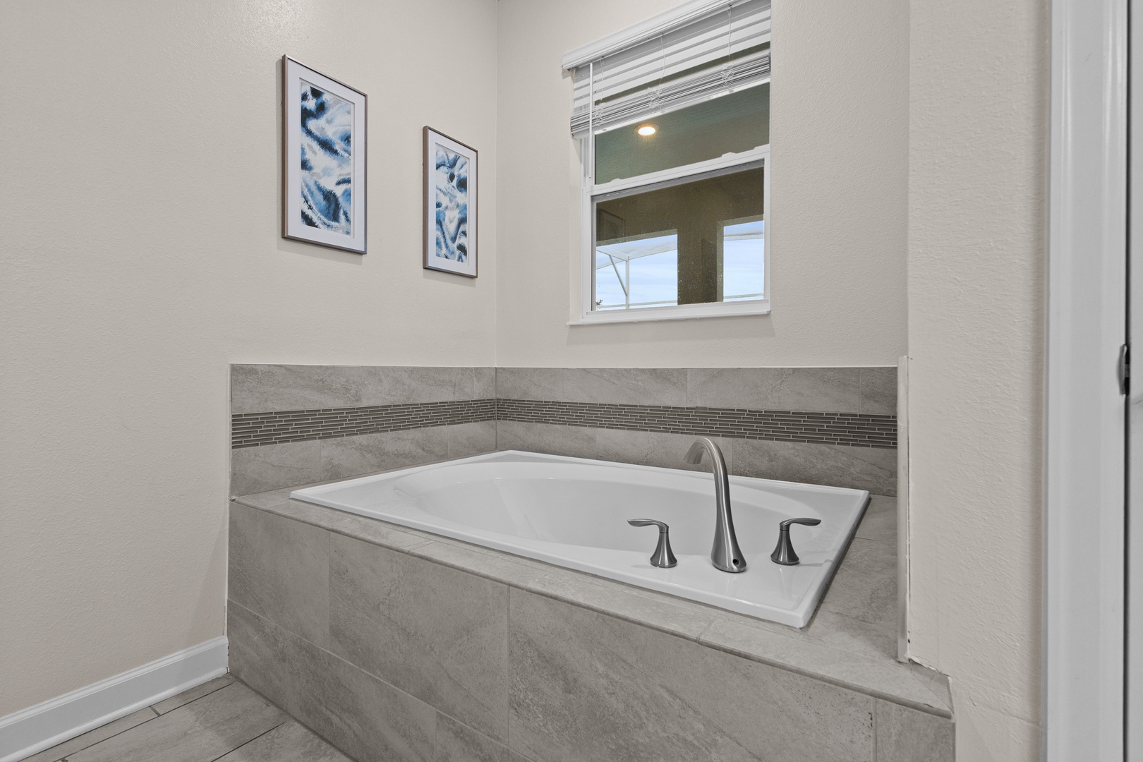 Sink into your private soaking tub surrounded by elegant marble finishes and calming blue artwork for the perfect evening retreat.
