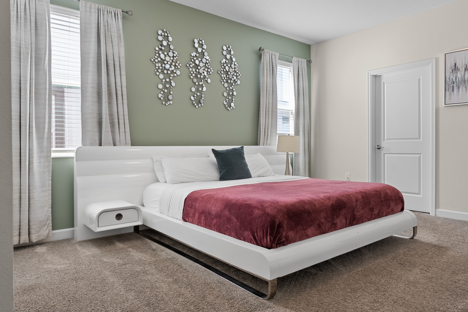 Unwind in your modern bedroom featuring a plush white platform bed with elegant burgundy accents and natural light.