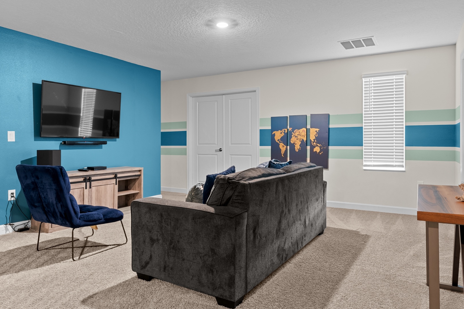 Unwind in your stylish living space with plush seating, large TV, and vibrant blue accent wall perfect for movie nights.