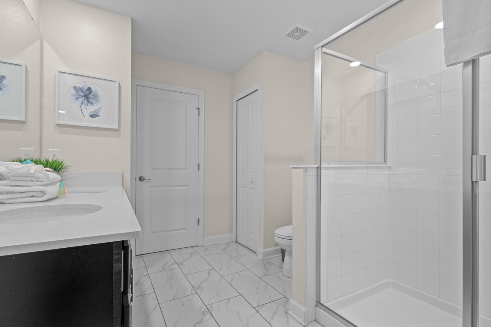 Refresh in your spacious private bathroom featuring a modern glass shower and elegant marble-style flooring.