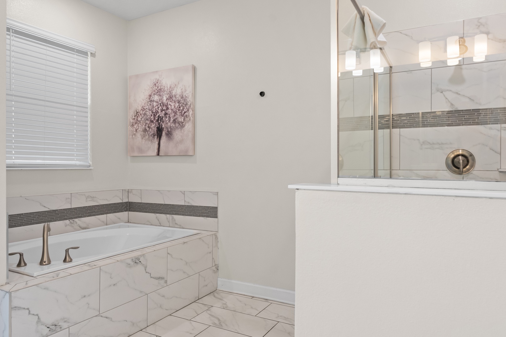Unwind in your elegant marble bathroom featuring a deep soaking tub and glass-enclosed shower with modern fixtures.