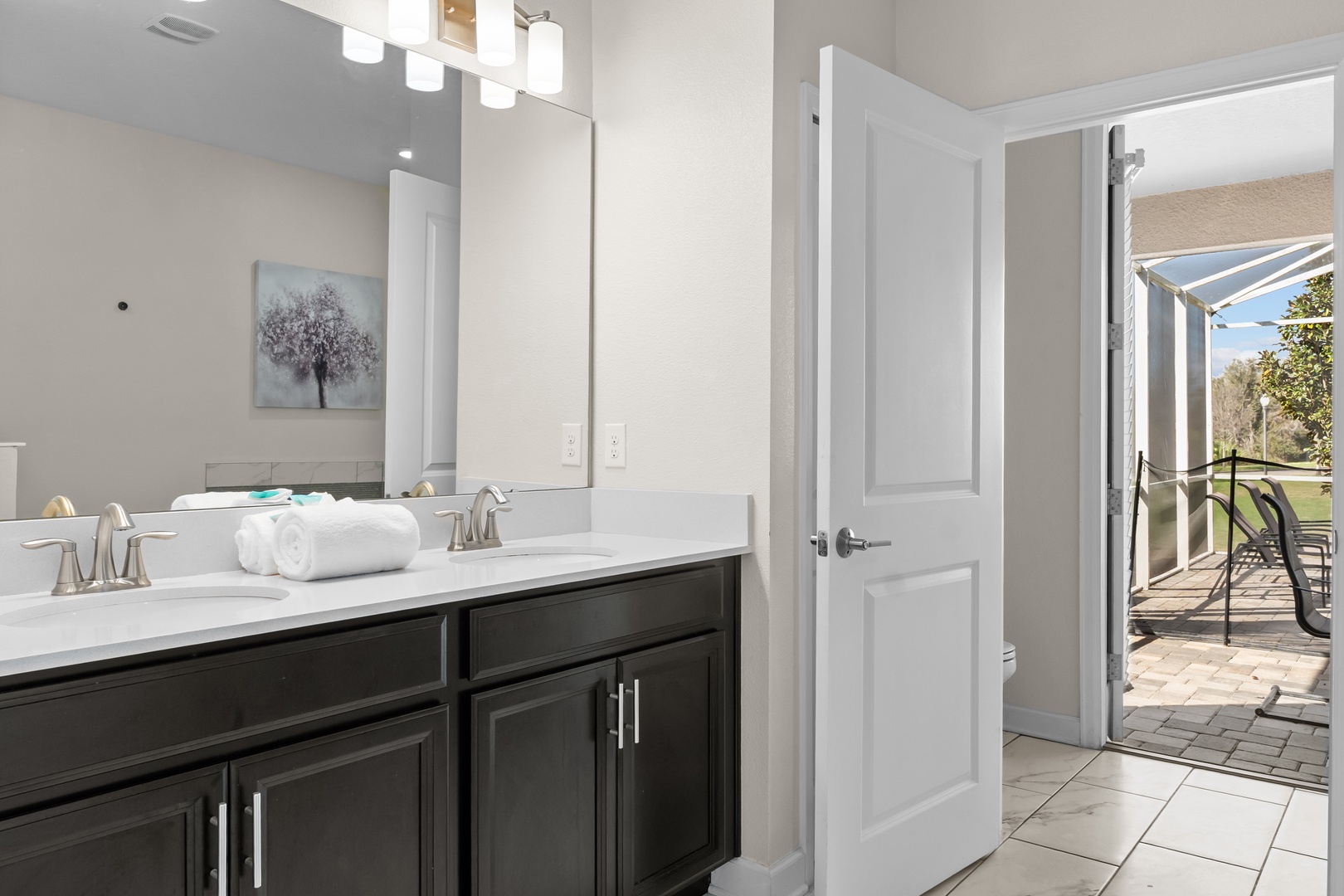 Your spacious bathroom features dual vanities with elegant lighting, fresh towels, and opens to your private balcony for morning light.