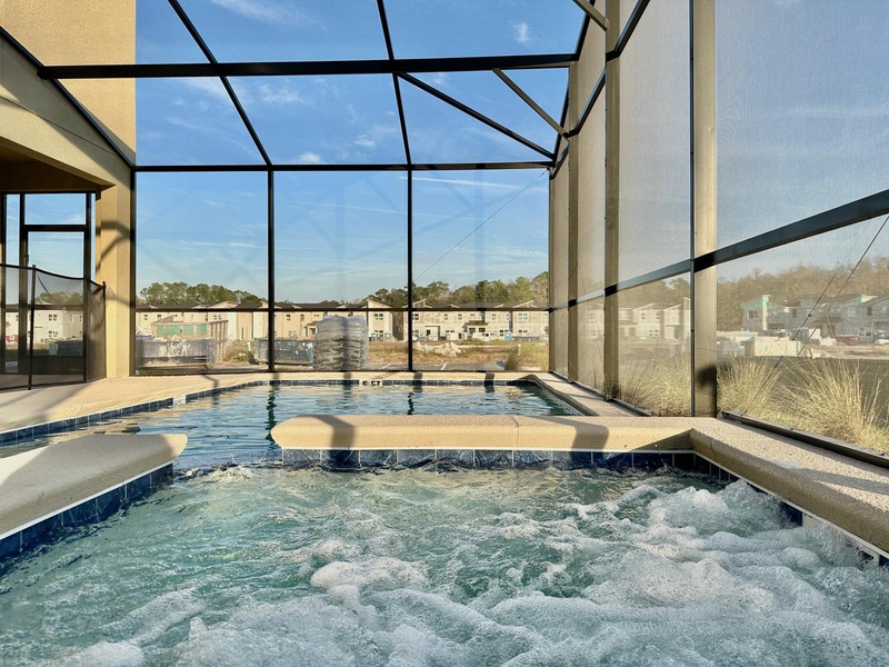 Soak in your private hot tub while enjoying panoramic views through floor-to-ceiling glass walls in this stunning screened enclosure.