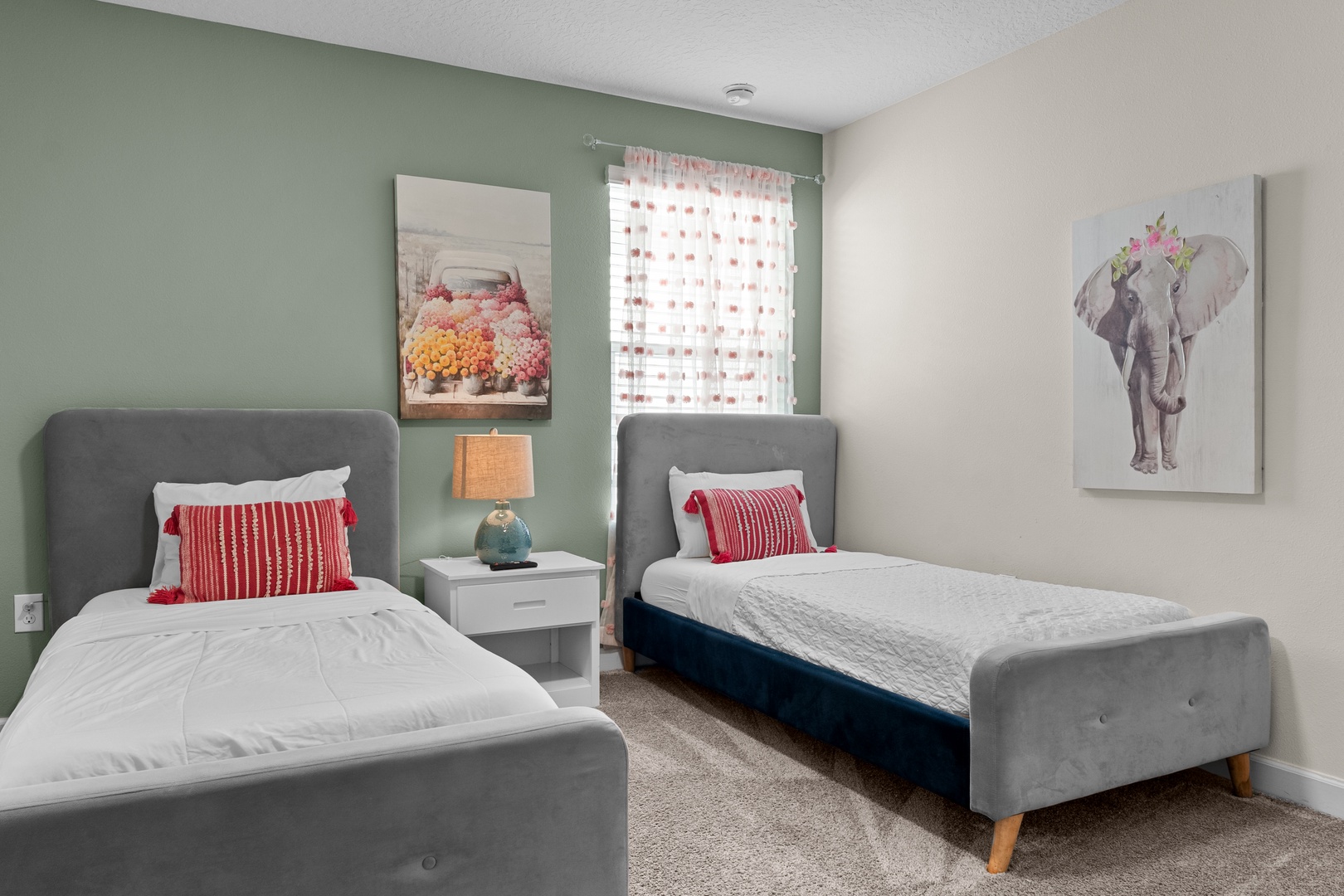 Your cozy twin bedroom features comfortable beds with cheerful red pillows and whimsical art creating the perfect space to unwind.