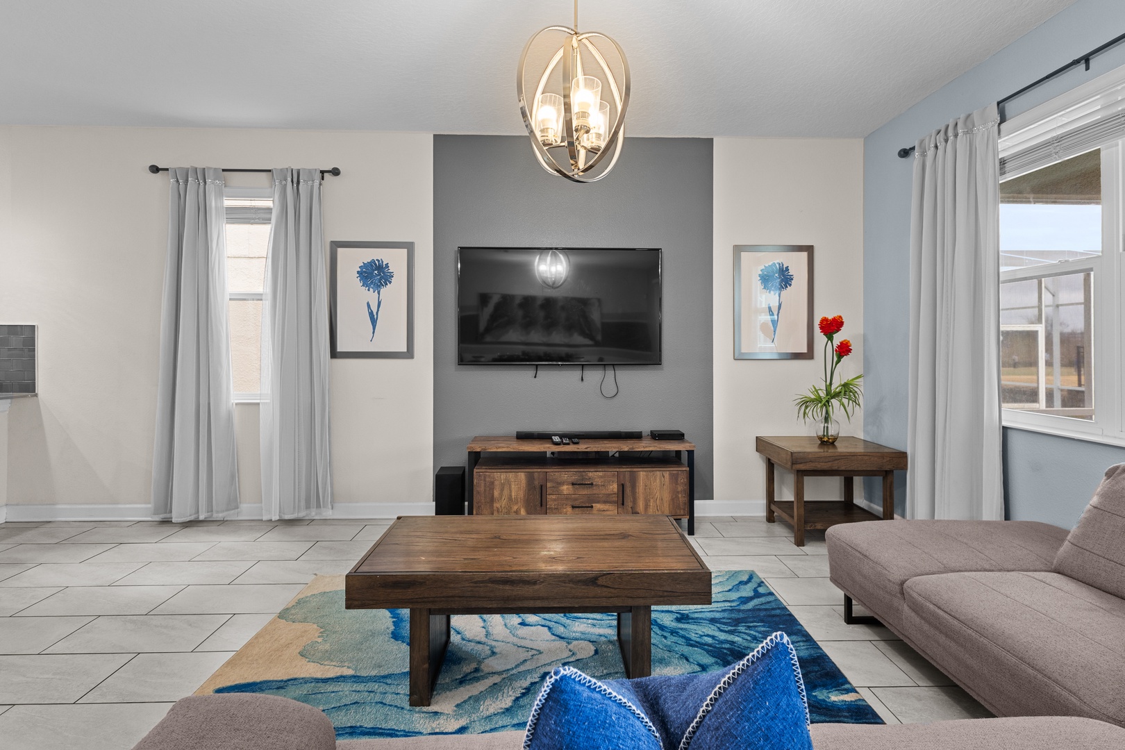 Unwind in your stylish living space where modern comfort meets coastal charm, featuring a cozy sofa and entertainment center for memorable evenings.