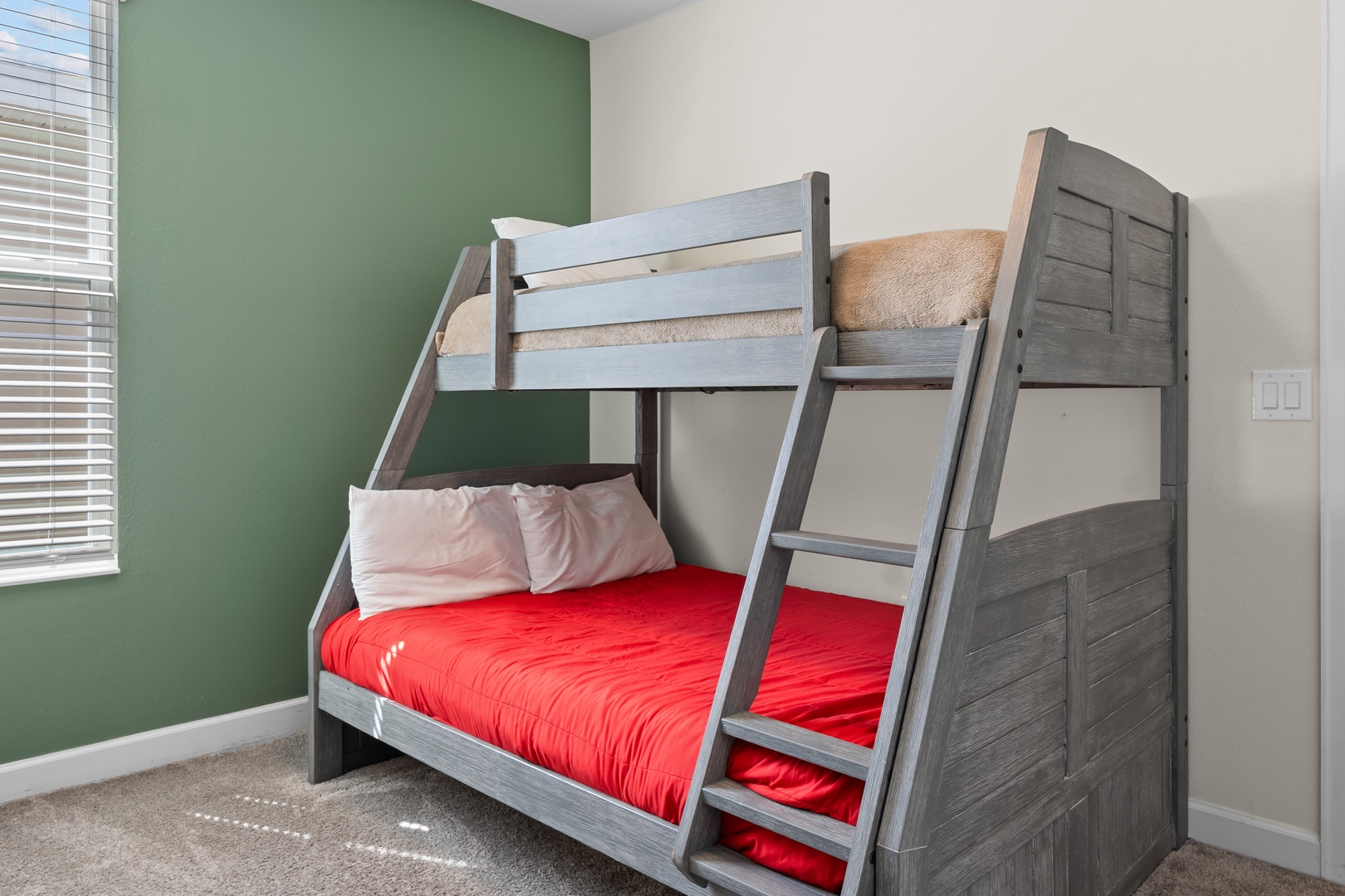 Your kids will love this stylish bunk bed setup with vibrant red bedding and cozy twin top bunk for perfect family memories.
