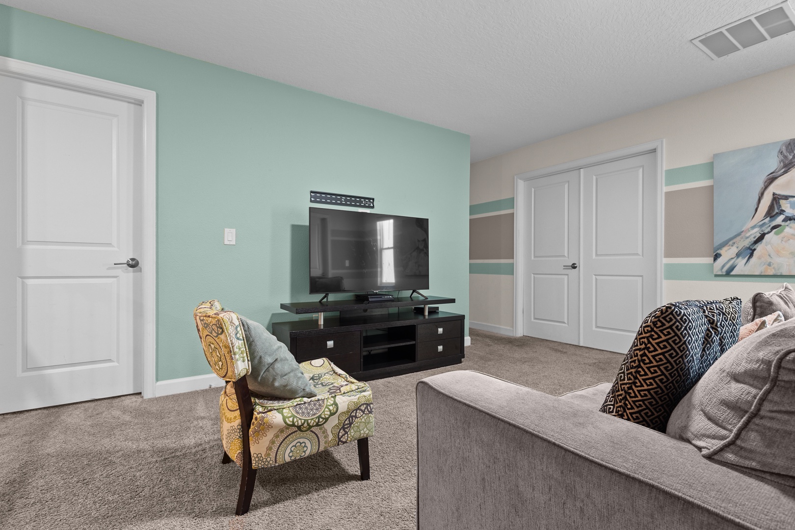 Unwind in your cozy living room with plush seating, a large TV for movie nights, and soothing mint-green accent walls that create the perfect relaxing retreat.