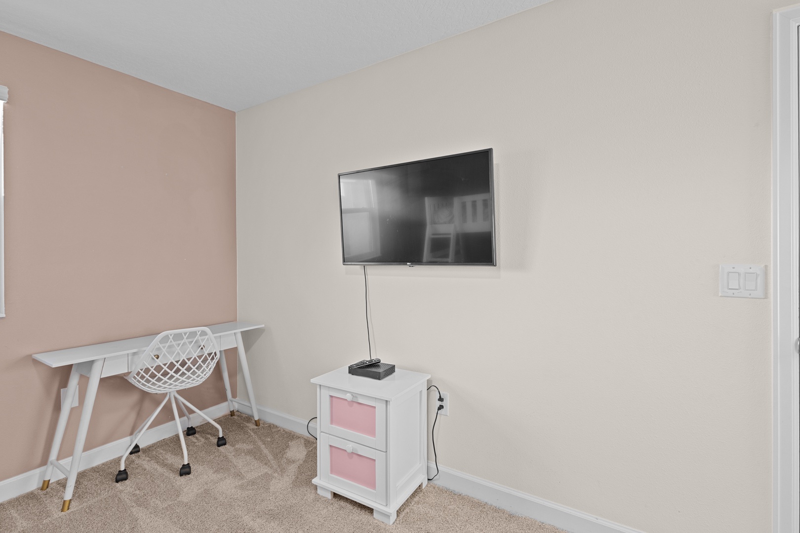 Your dedicated workspace features a modern desk and comfortable chair, while the wall-mounted TV adds entertainment after productive days.