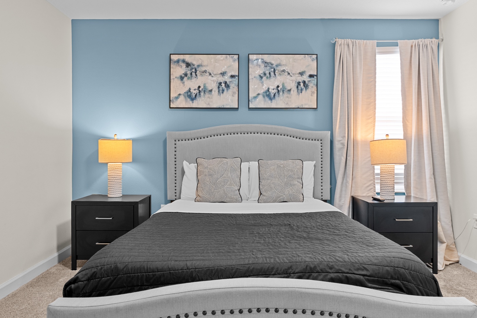 Sink into this serene bedroom where soft blue walls and warm bedside lighting create your perfect retreat after exploring.