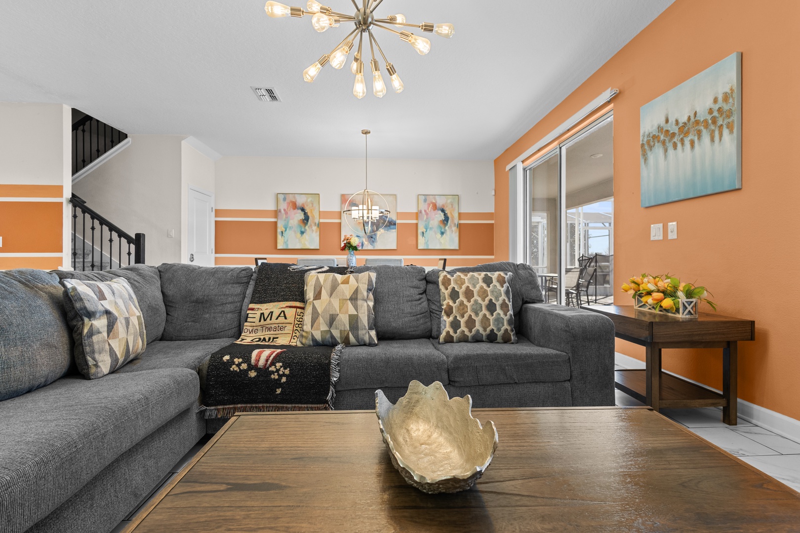 Sink into the plush sectional sofa and admire the modern chandelier overhead in your vibrant, thoughtfully decorated living space.