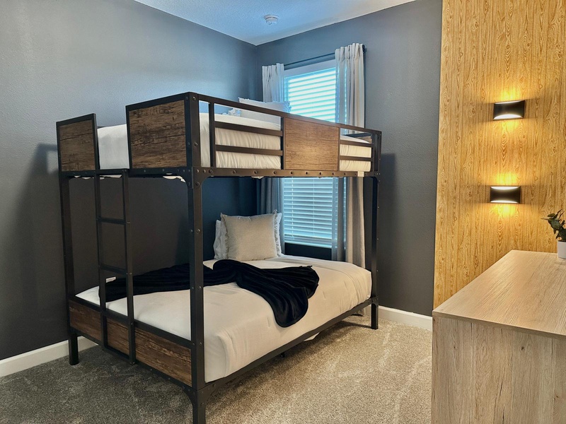 Your kids will love this stylish bunk bed room with warm wood accents and modern wall lighting, perfect for family adventures.