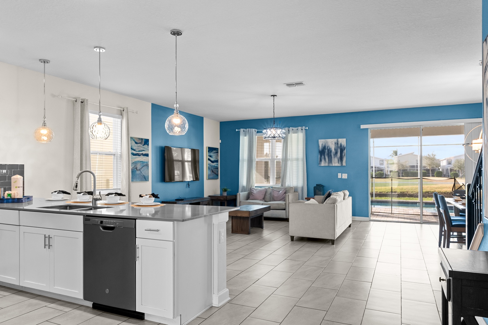 Your open-concept living space flows seamlessly from kitchen to living room, with vibrant blue walls and modern finishes creating a cheerful, relaxing atmosphere.