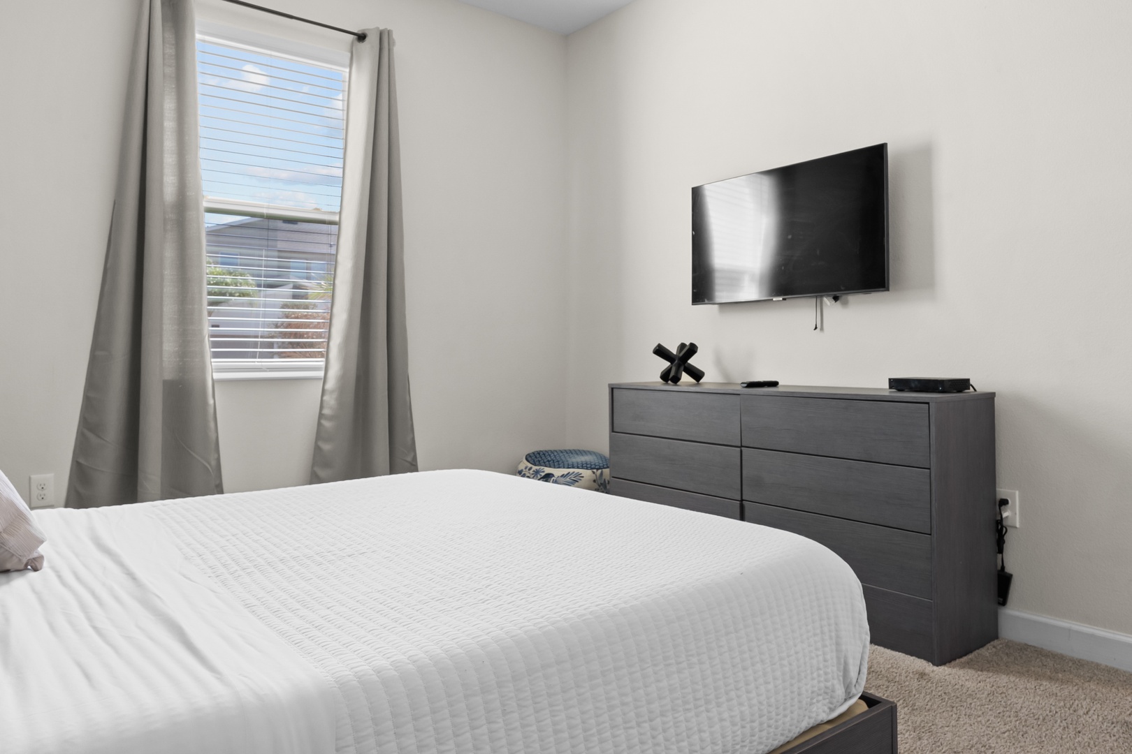 Relax in your peaceful bedroom with crisp linens, modern furnishings, and a wall-mounted TV for your entertainment.