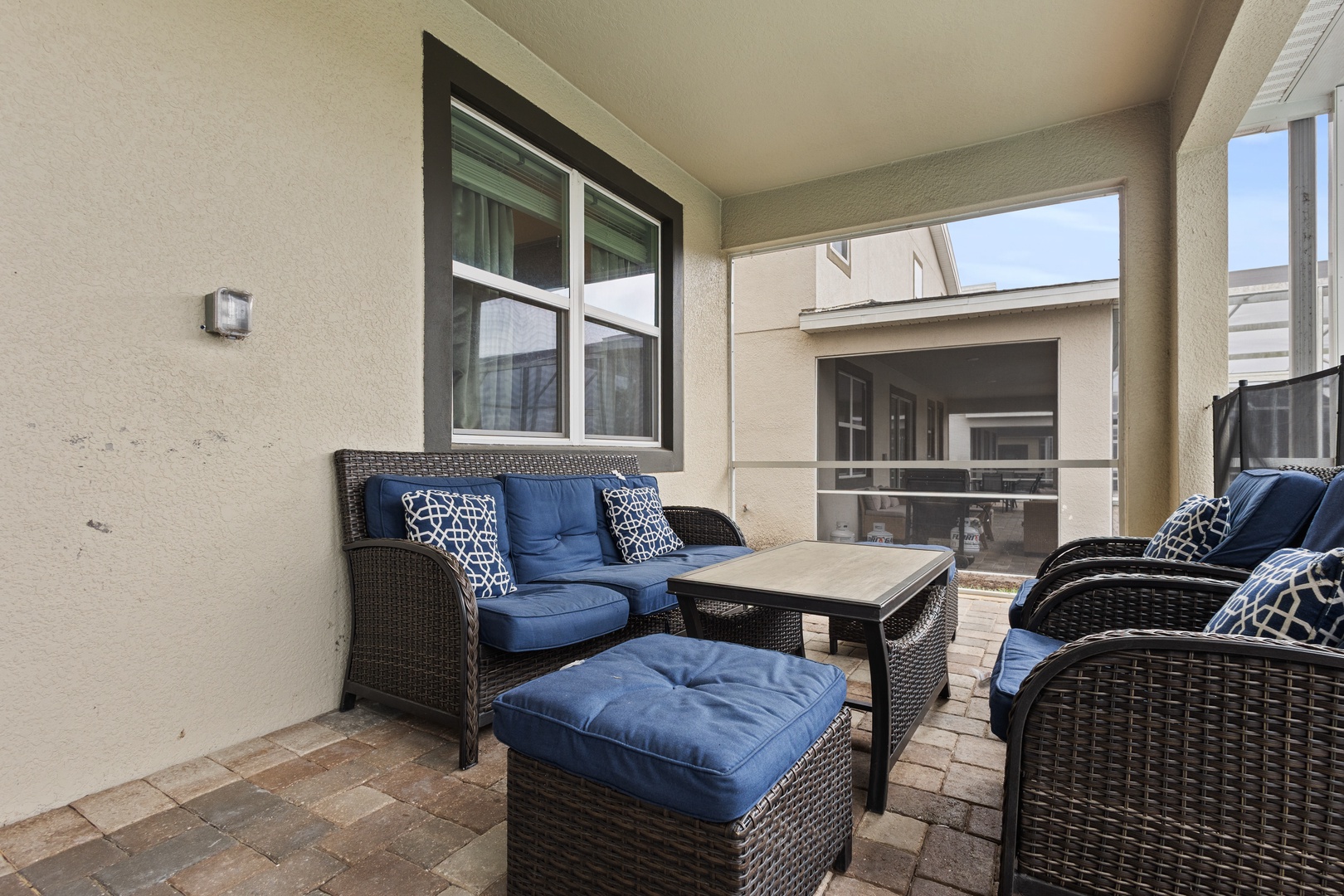 Unwind on your private patio with plush navy seating and stylish wicker furniture, perfect for morning coffee or evening relaxation.