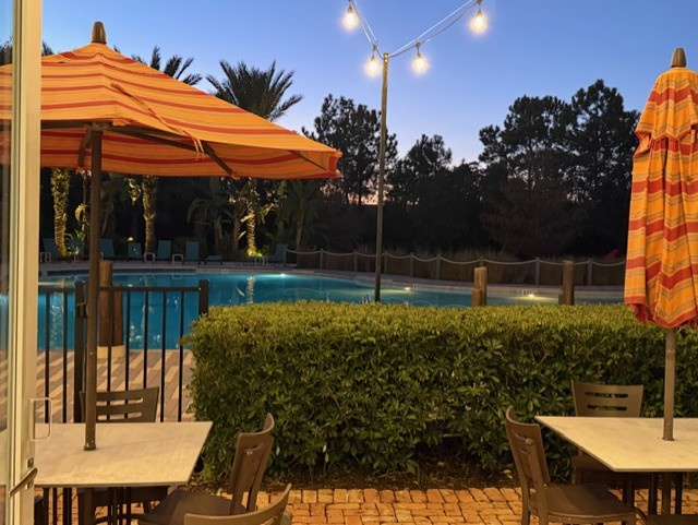 Your evening poolside retreat awaits with string lights creating magical ambiance over the sparkling water and comfortable seating.