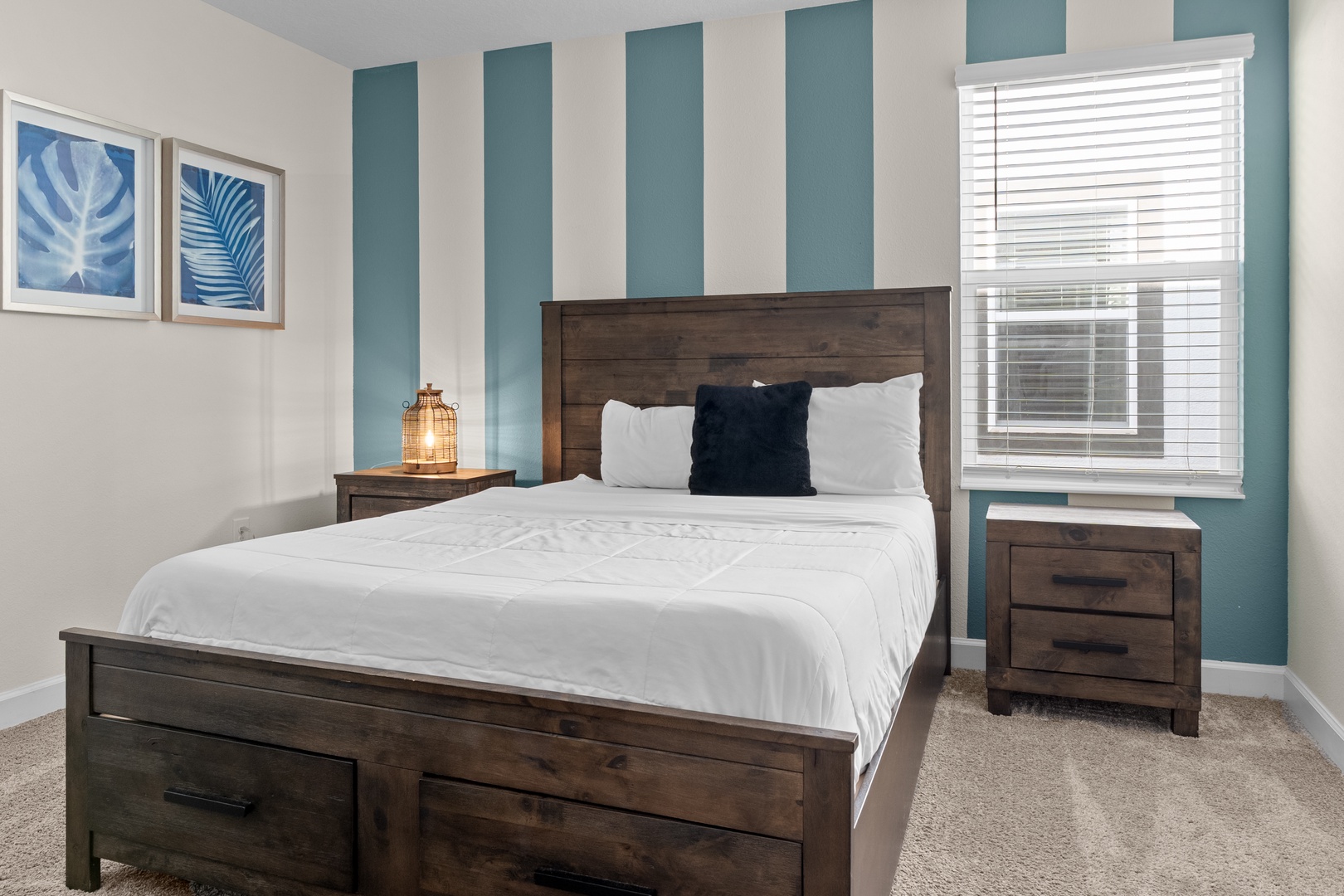 Sink into crisp white linens in your peaceful bedroom, where coastal-inspired stripes and warm wood furniture create the perfect retreat.