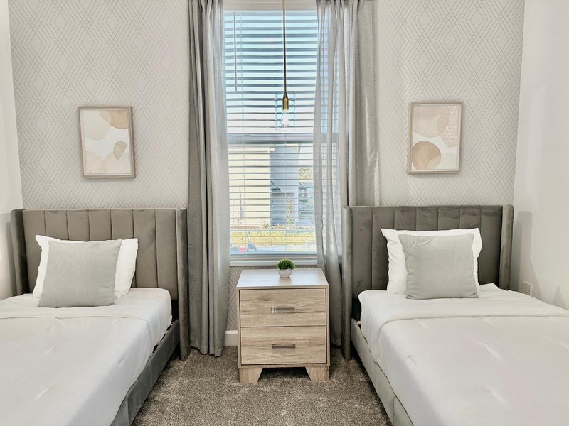 Your twin beds offer crisp linens and modern comfort, while gentle natural light streams through the window to create a peaceful retreat.