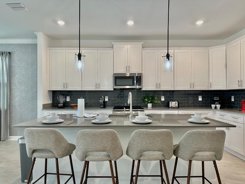 Your modern kitchen features white cabinets, granite counters, and stylish seating perfect for morning coffee or casual dining together.