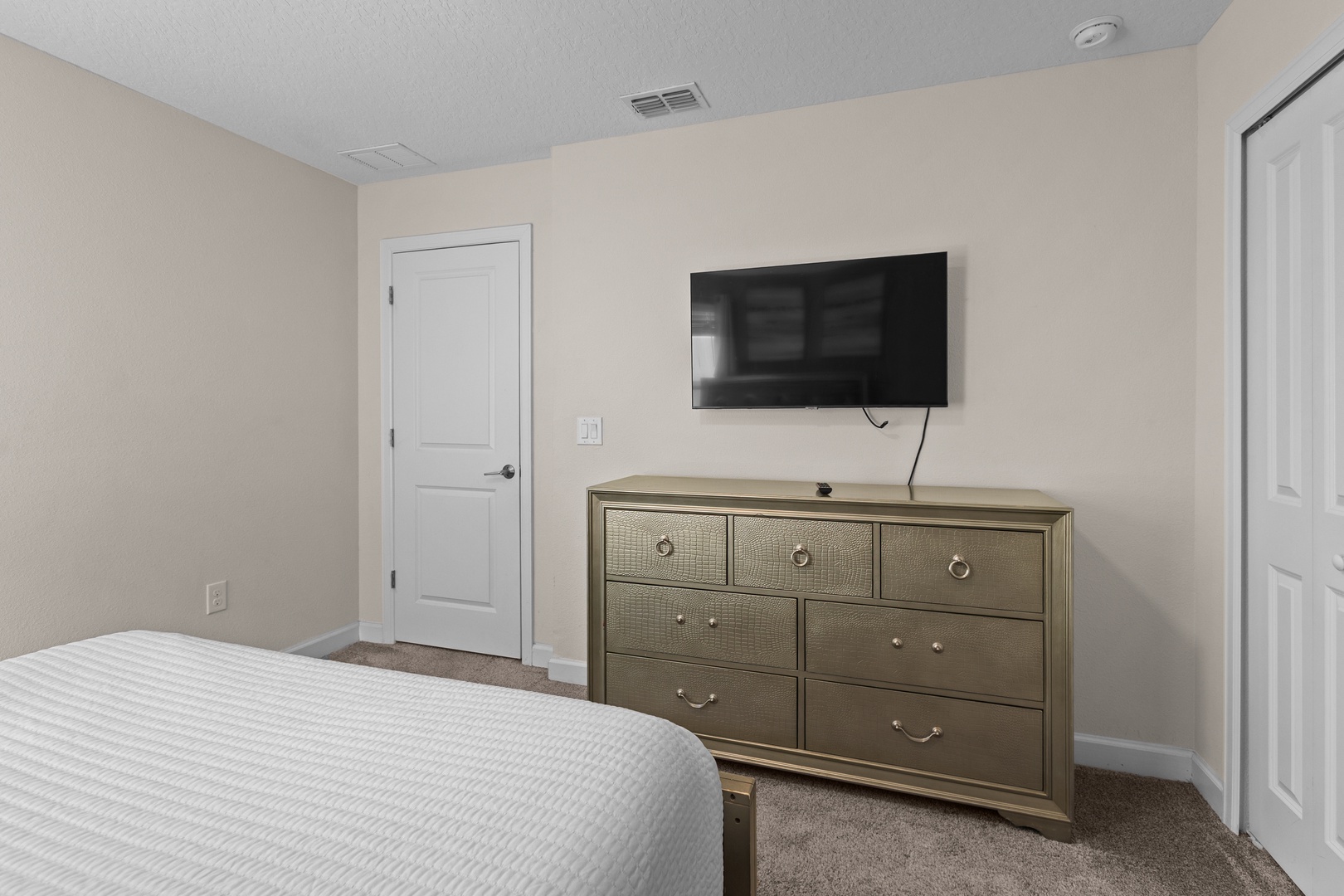 Unwind in your elegant bedroom featuring a wall-mounted TV and stylish dresser for all your belongings.