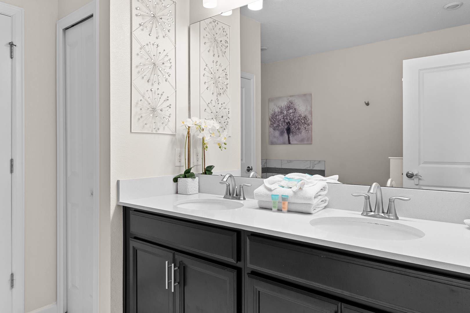 Refresh in your stylish dual-sink bathroom featuring elegant marble countertops, thoughtful amenities, and beautiful botanical artwork for a spa-like experience.