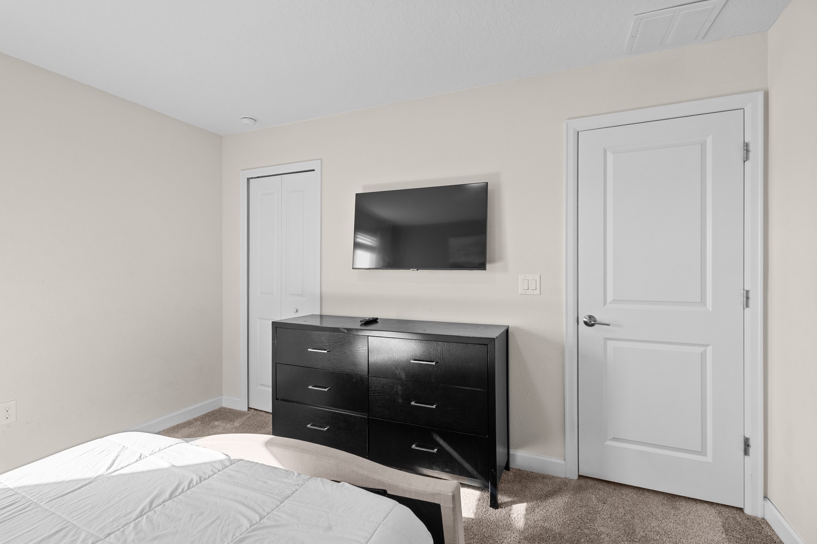 Unwind in your serene bedroom with modern amenities - a sleek dresser provides ample storage while your wall-mounted TV offers perfect evening entertainment.