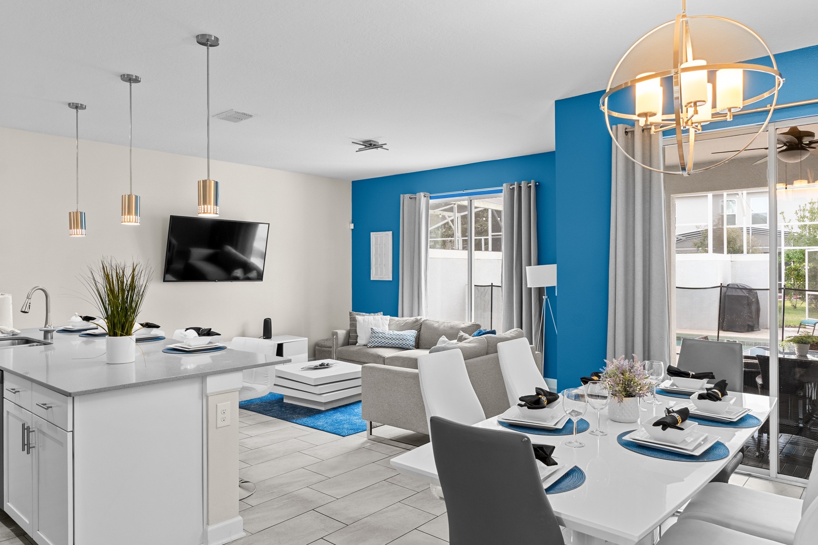 Your open-concept haven blends modern kitchen, cozy living, and elegant dining areas with vibrant blue accents and natural light throughout.