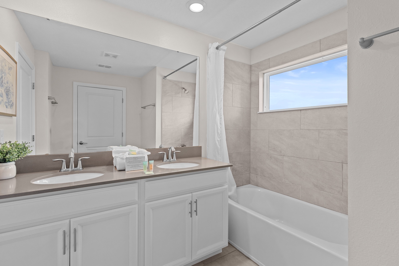 Unwind in your spacious bathroom with dual sinks, a relaxing soaking tub, and natural light streaming through the window.