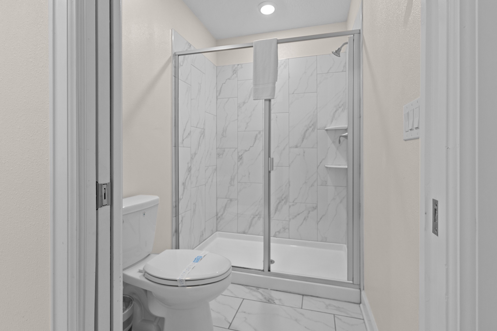Step into your pristine marble-accented bathroom with a spacious walk-in shower and modern fixtures for your comfort.