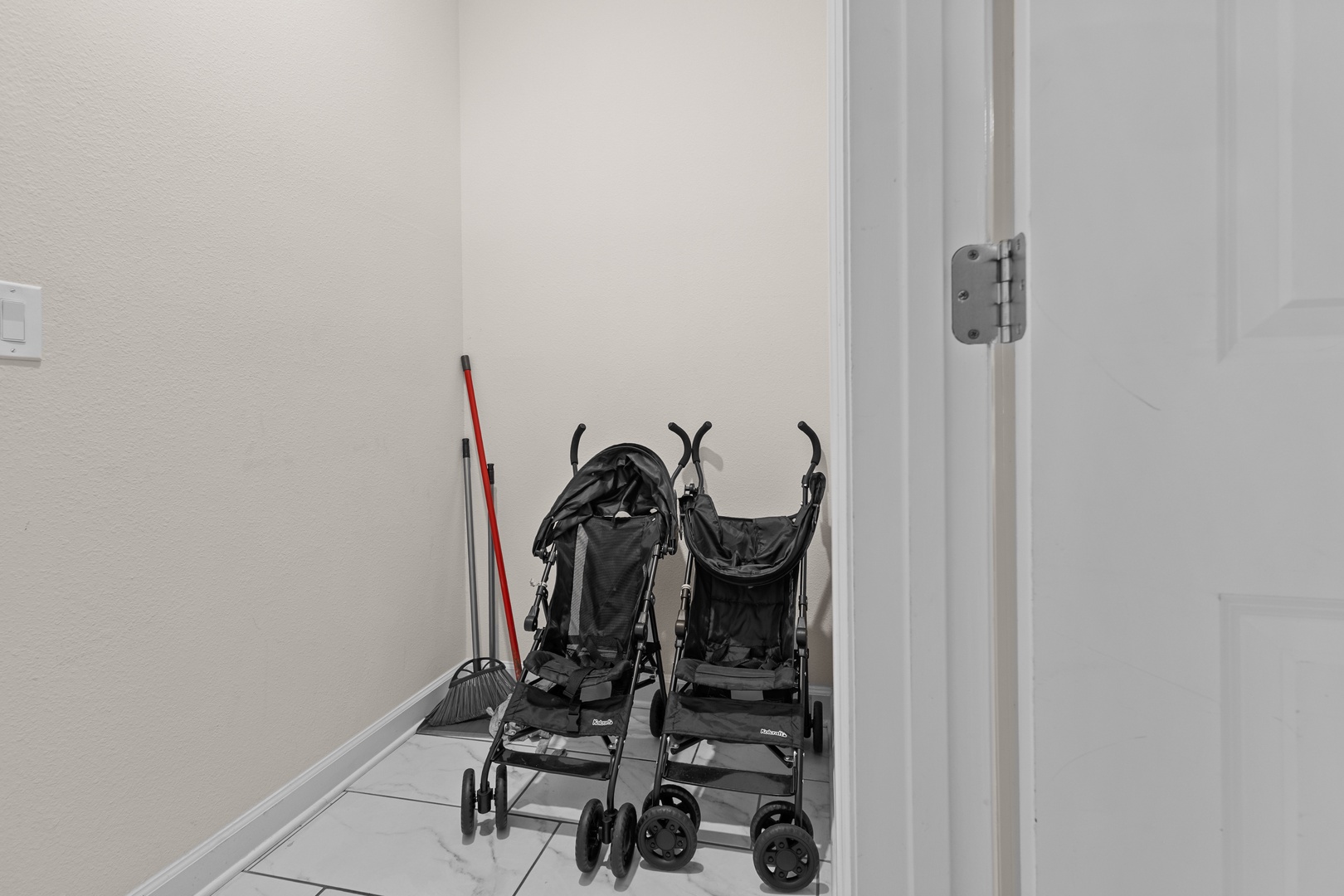Your family gear has a dedicated spot - twin strollers and cleaning supplies stored safely in this convenient utility closet.