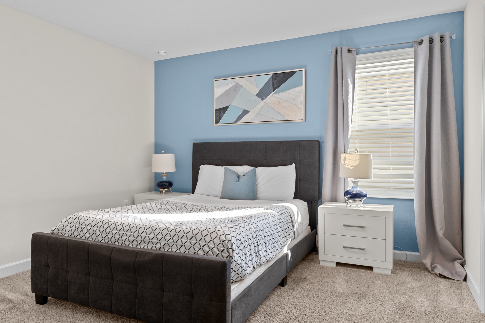 Drift off in this serene bedroom where calming blue walls meet crisp white linens and plush carpet beneath your feet.