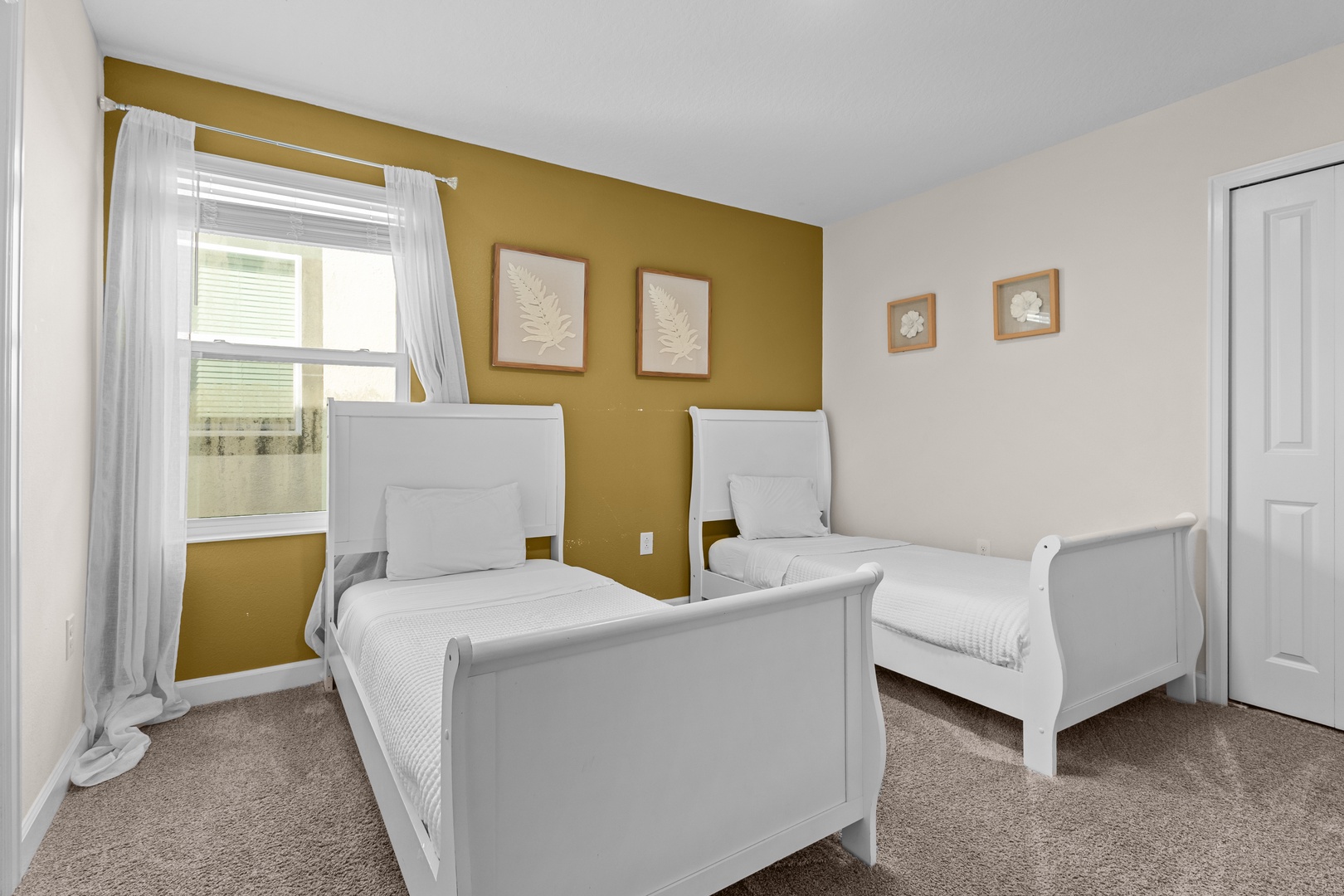Rest peacefully in your comfortable twin bedroom featuring white sleigh beds, botanical artwork, and warm natural light streaming through the windows.