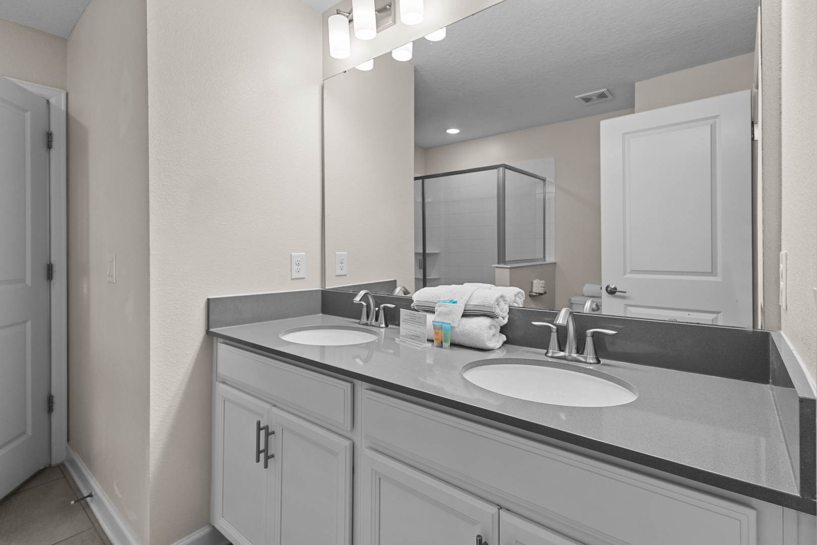 Step into your pristine bathroom featuring dual sinks and modern fixtures, where fresh towels await your arrival.