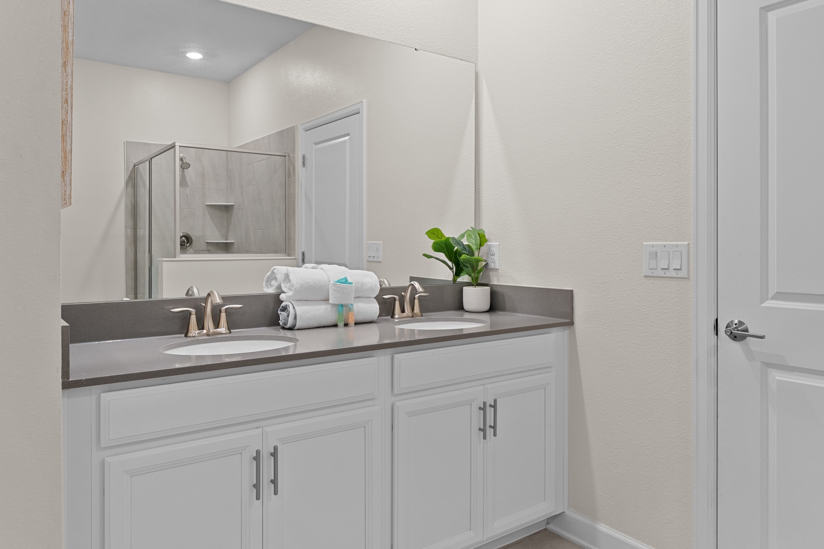 Relax in your spacious master bathroom with dual vanities, fresh towels, and modern finishes for your comfort.