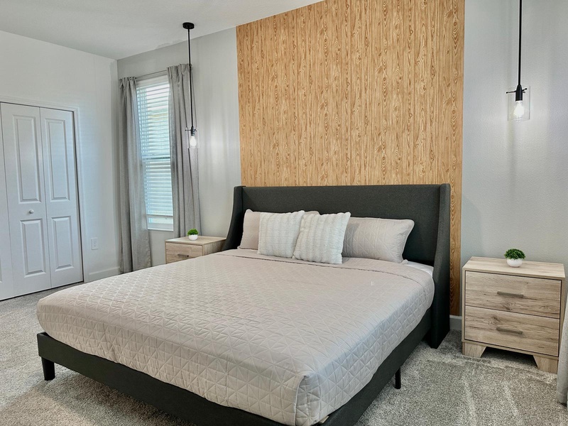 Your serene bedroom features a plush bed with soft linens and modern wood accents for your restful stay.