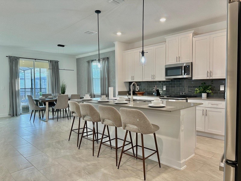 Your modern kitchen flows seamlessly into the dining area, featuring sleek white cabinets, granite countertops, and stylish bar seating perfect for casual meals.