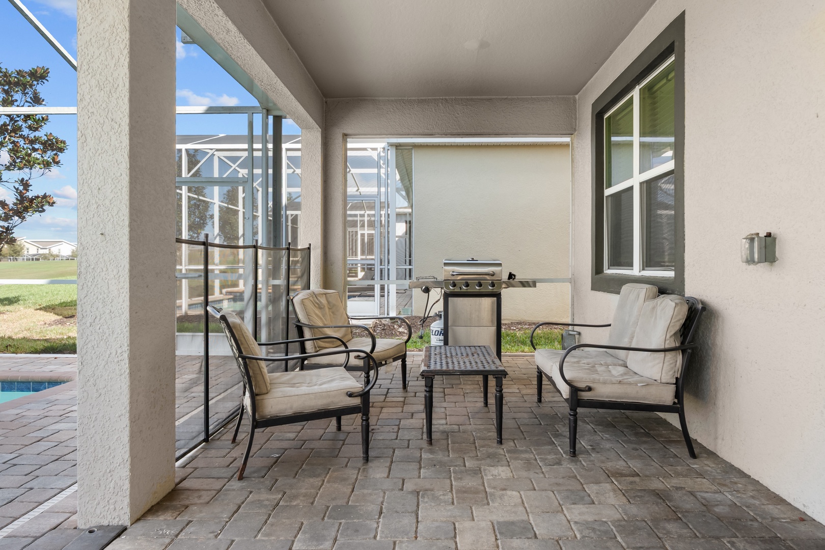 Relax in your private covered patio with comfortable seating and BBQ grill, perfect for outdoor dining while staying cool in the shade.