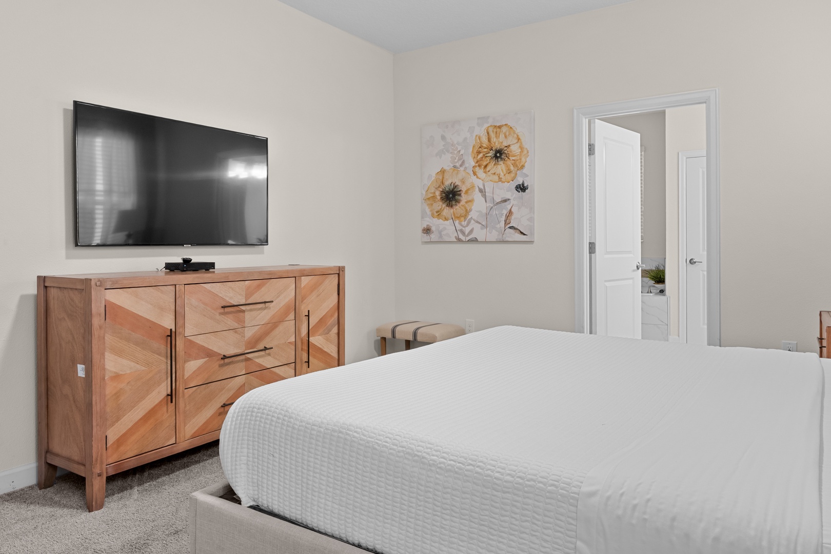 Unwind in your serene bedroom with crisp white linens, warm wood accents, and modern entertainment—your peaceful retreat awaits.