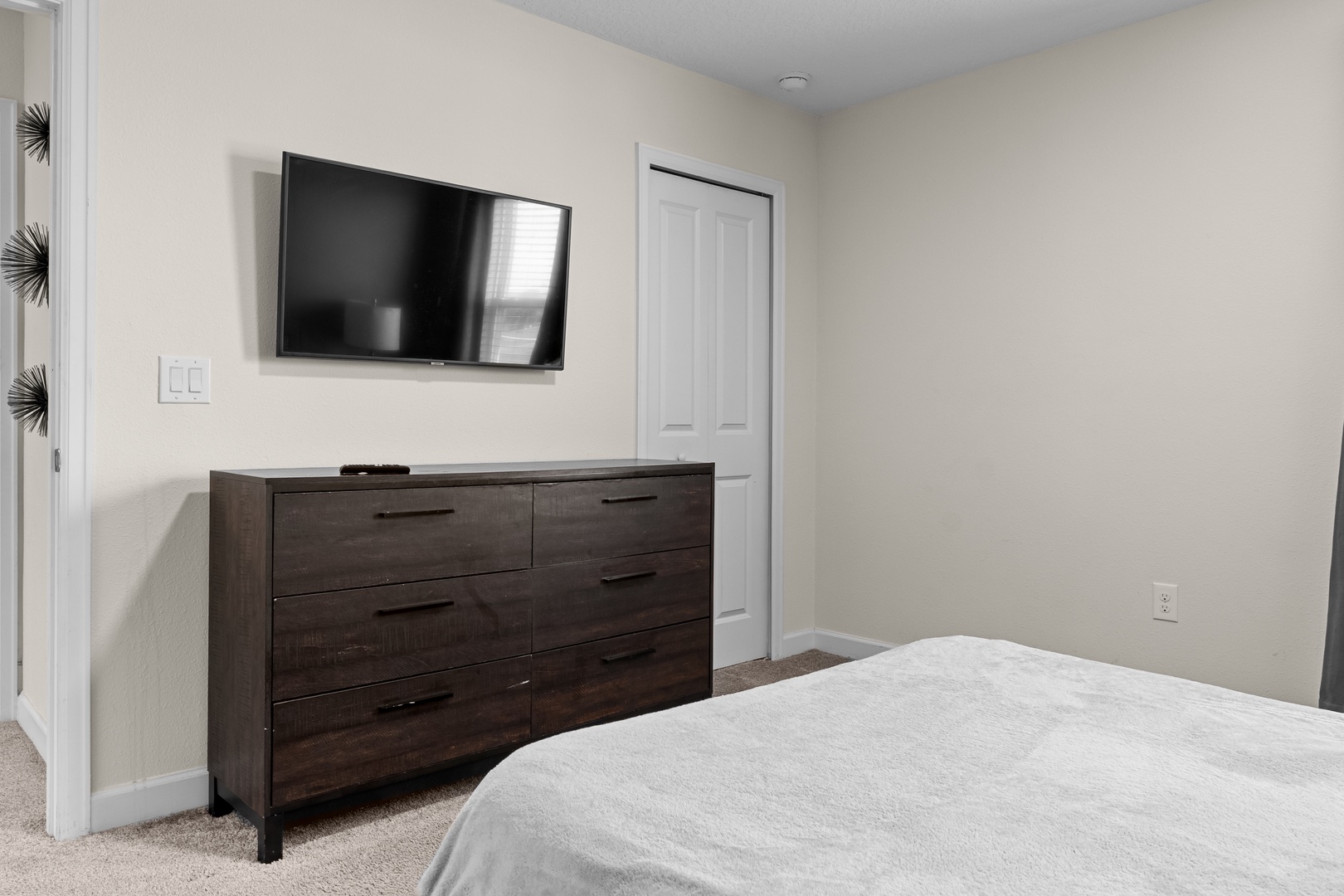 Your cozy bedroom features a wall-mounted TV and spacious dresser, perfect for unwinding after exploring the area.
