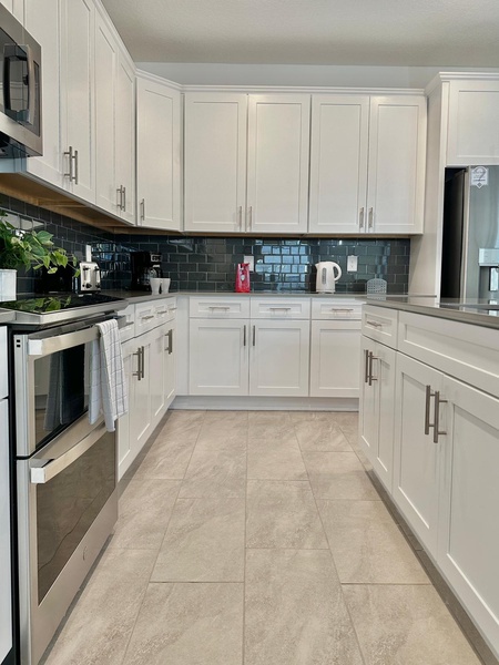 Cook memorable meals in this bright, modern kitchen featuring crisp white cabinetry, sleek subway tile backsplash, and full appliances.