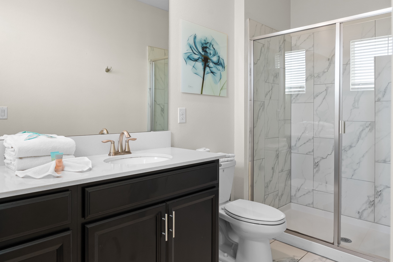 Refresh in your elegant bathroom featuring marble shower tiles, plush towels, and modern amenities.